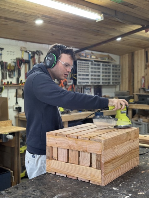 Liam sanding a board in the workshop